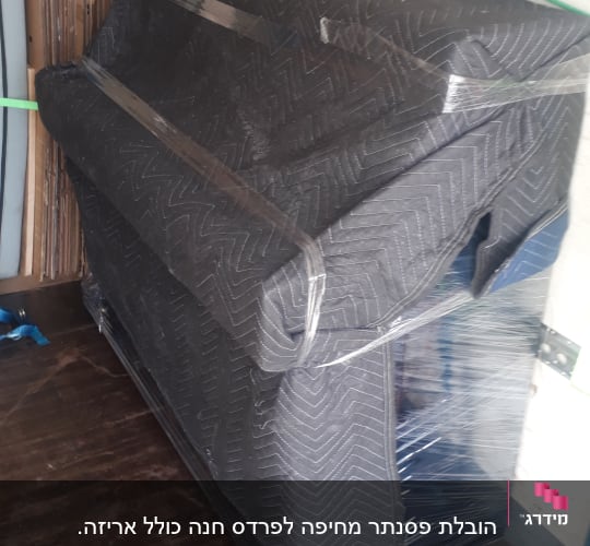 פסנתר עטוף בשמיכה ומאובטח ברצועות בתוך משאית